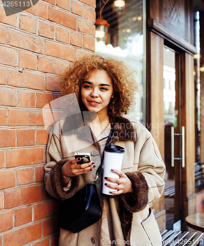 Image of young pretty african american women drinking coffee outside in c