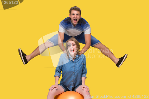 Image of Portrait of a young couple jumping against yellow background