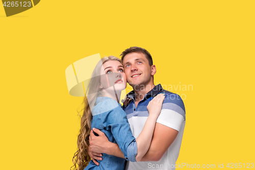 Image of Portrait of a young couple standing against yellow background