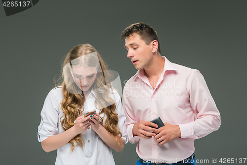 Image of Business concept. The two young colleagues holding mobile phones on gray background