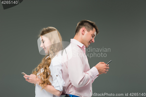 Image of Business concept. The two young colleagues holding mobile phones on gray background