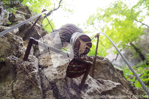 Image of Woman climbing on the rocky route up the mountain.