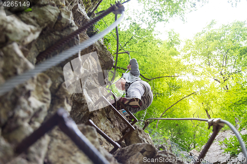 Image of Woman climbing on the rocky route up the mountain.