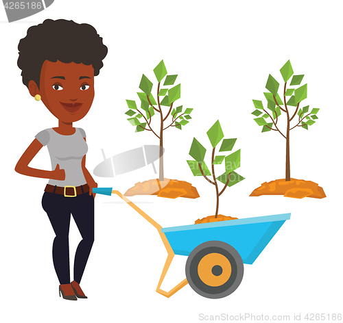 Image of Woman pushing wheelbarrow with plant.