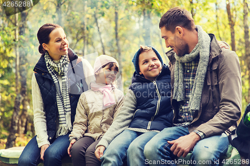 Image of happy family sitting on bench and talking at camp
