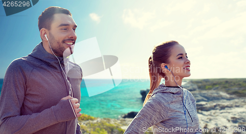 Image of happy couple with earphones running in city