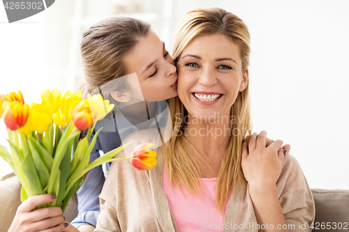 Image of happy girl giving flowers to mother at home