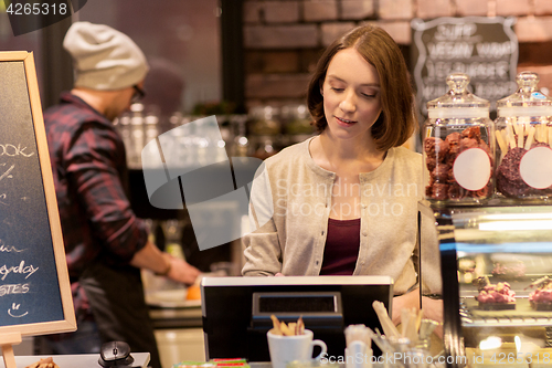 Image of woman bartender at cafe or coffee shop cashbox