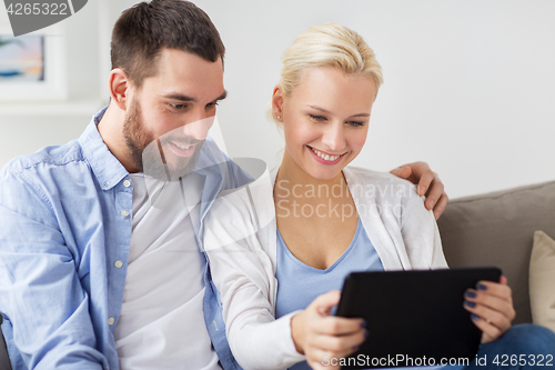 Image of smiling happy couple with tablet pc at home