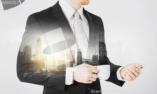 Image of businessman with smartphone and cup of coffee