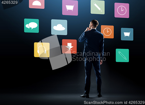 Image of businessman in suit looking at virtual menu icons