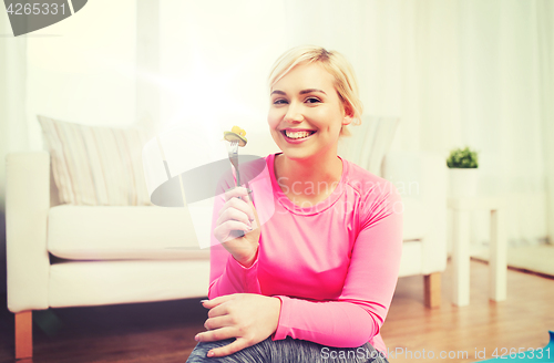 Image of smiling young woman eating salad at home