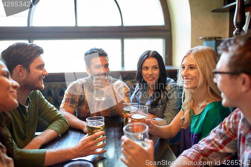 Image of happy friends drinking beer at bar or pub