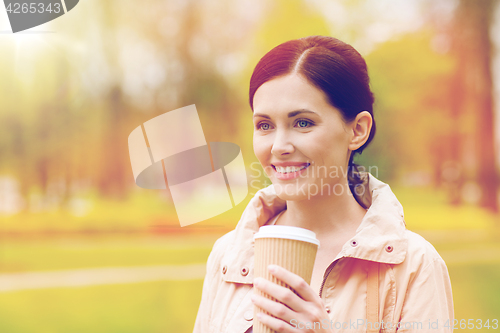 Image of smiling woman drinking coffee in park