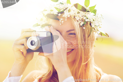 Image of happy woman with film camera in wreath of flowers