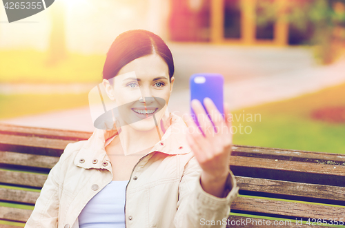 Image of smiling woman taking picture with smartphone