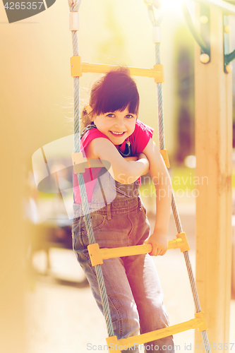 Image of happy little girl climbing on children playground