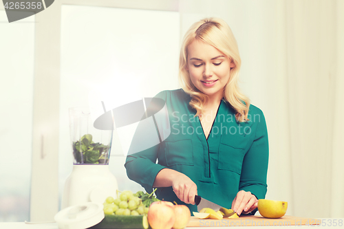 Image of smiling woman with blender cooking food at home