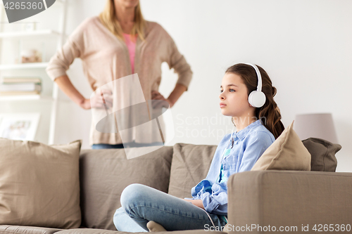 Image of girl with earphones and angry mother at home