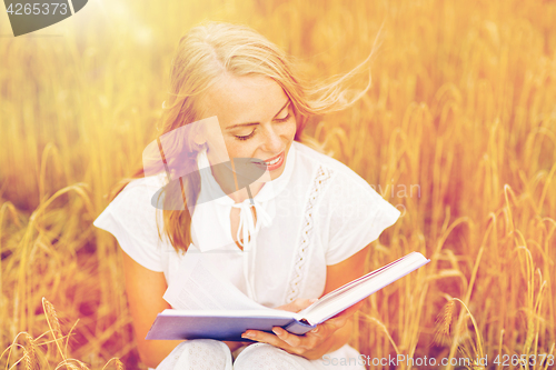 Image of smiling young woman reading book on cereal field