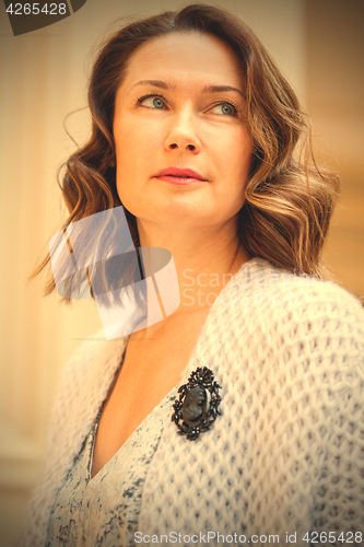 Image of beautiful middle-aged woman in gray knitted overcoat with black 
