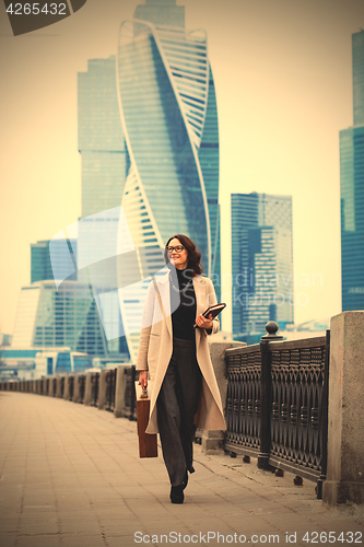 Image of Smiling beautiful woman in a light coat against the backdrop of 