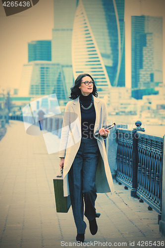 Image of Beautiful woman in a light coat with a wooden case