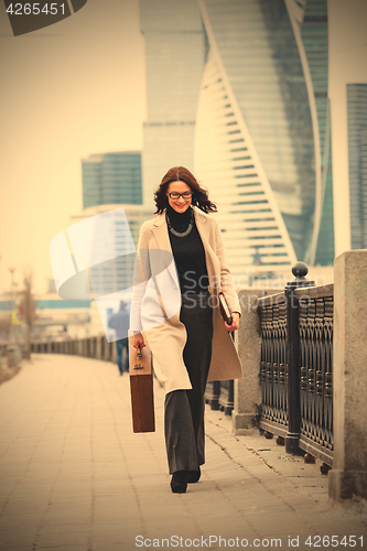 Image of Smiling dark-haired woman in a bright coat is on the waterfront