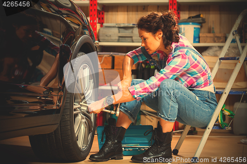 Image of woman car mechanic in blue jeans jumpsuit
