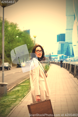 Image of beautiful business woman in a light coat with a stylish wooden c