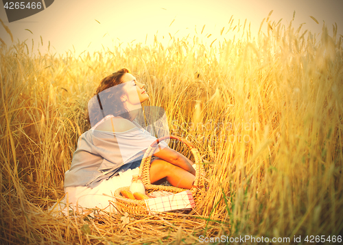 Image of Beautiful woman relaxes in a field among wheat ears