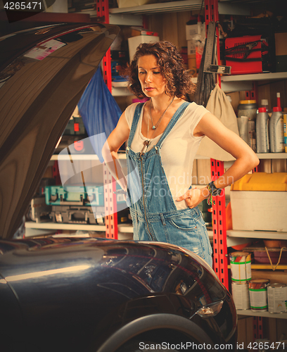 Image of pretty woman mechanic prepares the car for the travel