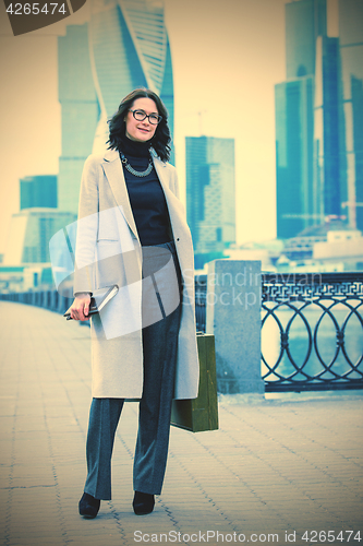 Image of Beautiful smiling woman in a light trendy coat on the waterfront