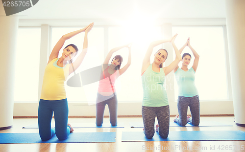 Image of happy pregnant women exercising on mats in gym