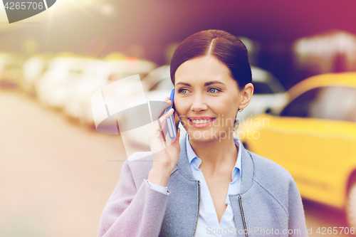 Image of smiling woman with smartphone over taxi in city