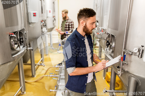 Image of men with clipboard at craft brewery or beer plant