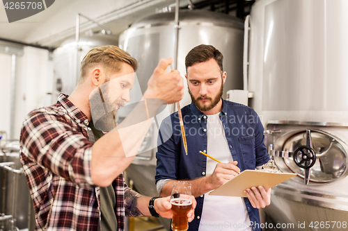 Image of men with pipette testing craft beer at brewery