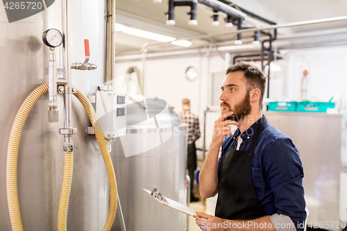 Image of man with clipboard at craft brewery or beer plant