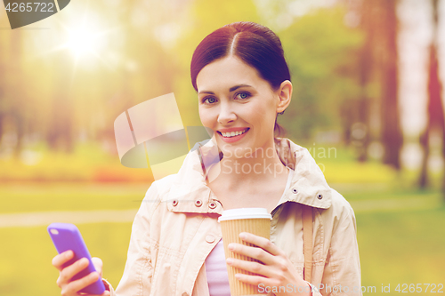 Image of smiling woman with smartphone and coffee in park