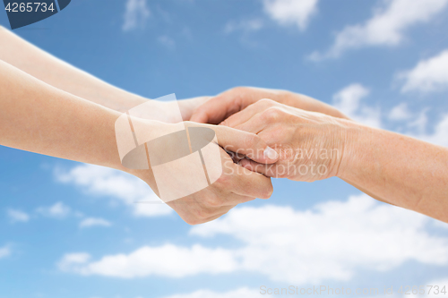 Image of close up of senior and young woman holding hands