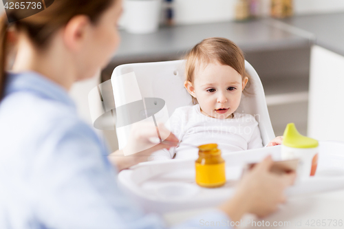 Image of happy mother feeding baby with puree at home