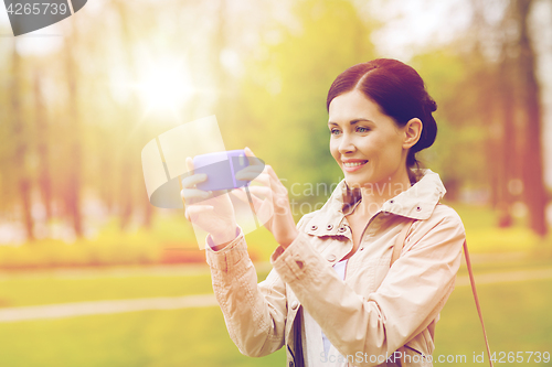 Image of smiling woman taking picture with smartphone