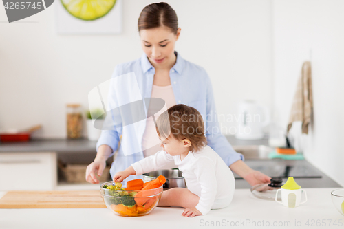 Image of happy mother and baby with food at home kitchen