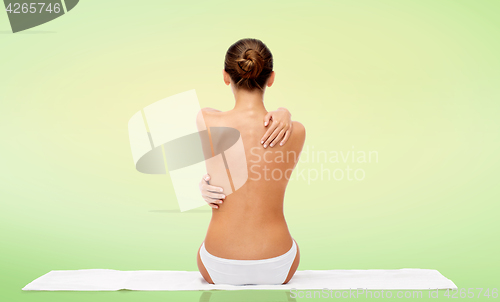 Image of beautiful topless young woman on towel from back