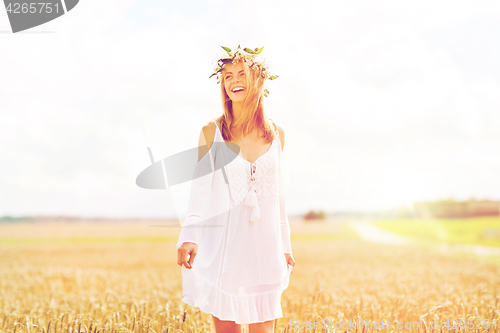 Image of happy young woman in flower wreath on cereal field