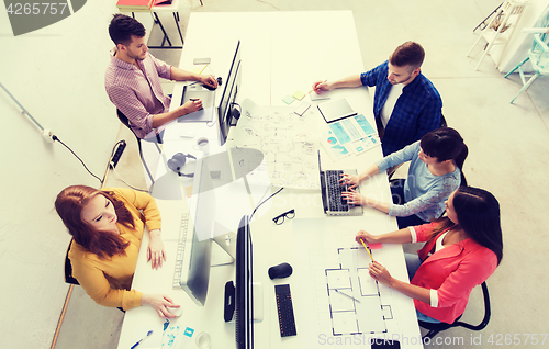 Image of creative team with computers, blueprint at office