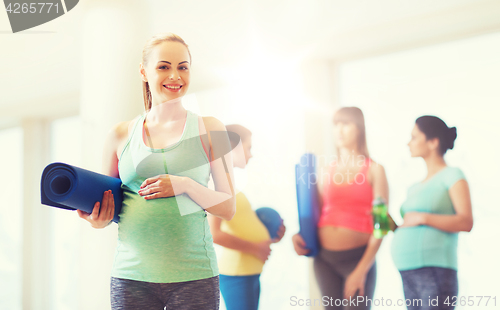 Image of happy pregnant woman with mat in gym