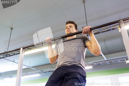 Image of man exercising on bar and doing pull-ups in gym