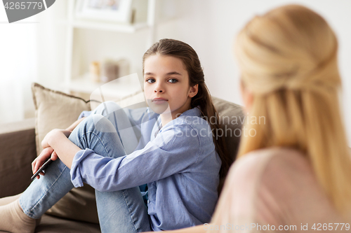 Image of sad girl with mother sitting on sofa at home