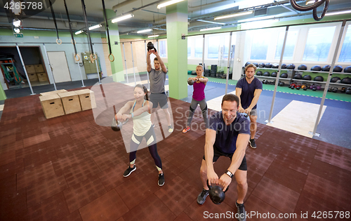 Image of group of people with kettlebells exercising in gym